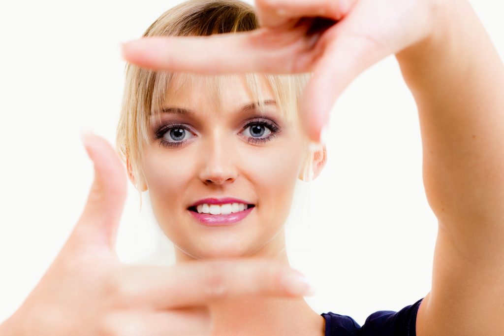 junge frau schaut durch fingerrahmen